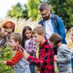 Group of school children with teacher on field trip in nature, learning science.