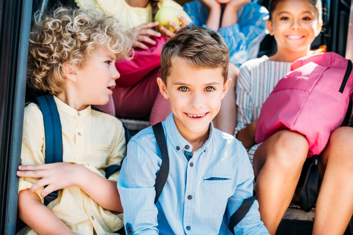 group of happy schoolchildren sitting on stairs
